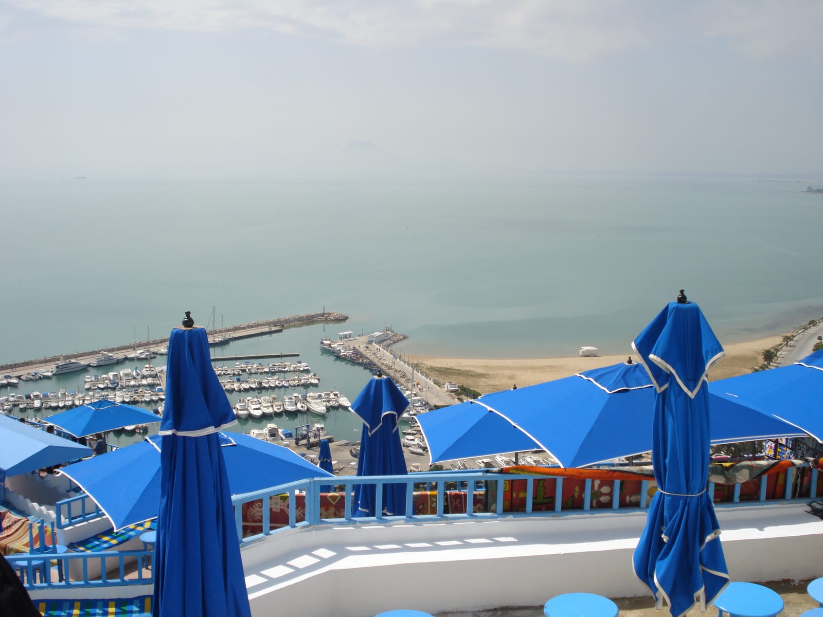 Blue parasols on a clifftop terrace above the marina
